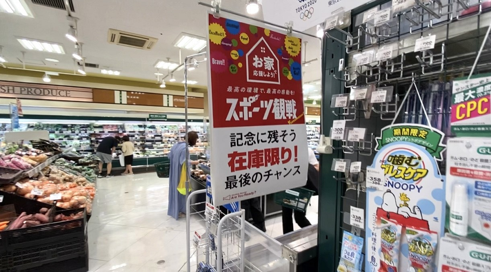 A notice in an Olympic souvenirs’ corner at a Tokyo supermarket encourages shoppers to watch sport and leave a memory by buying limited stock as it is last chance. (Supplied)