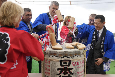 Japanese ambassador to Romania Hiroshi Ueda (right) along with Romanian officials breaks the cover of a sake barrel during a ceremony on the river Danube at the construction site of a suspension bridge across the Danube river, in Braila, Romania, Thursday, Aug. 26, 2021. (AP)