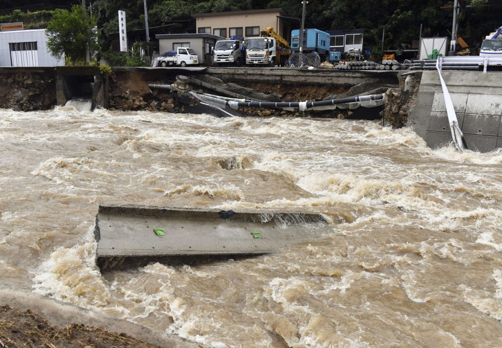 A road is damaged by the swollen Suzuhari river in heavy rain in Hiroshima, western Japan, Friday, Aug. 13, 2021. Torrential rain pounding southwestern Japan has triggered a mudslide and swallowed four people in Nagasaki and threatened the region with the risk of floods and more landslides, officials said Friday.(File photo/Kyodo News via AP)