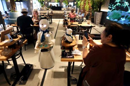 In this picture taken on August 17, 2021, a humanoid robot delivers drinks to customers at the Dawn Cafe in Tokyo. (AFP)