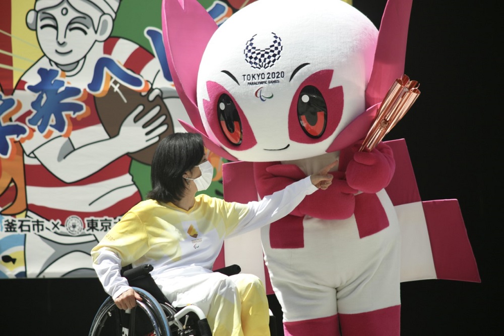 Tokyo 2020 torch relay ambassador Aki Taguchi interacts with the Tokyo 2020 Paralympic mascot Someity during a 