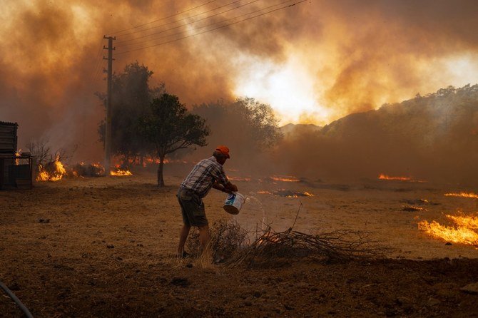 Men fight with an advancing fire on August 2, 2021 in Mugla, Marmaris district, as the European Union sent help to Turkey and volunteers joined firefighters in battling a week of violent blazes that have killed eight people. (AFP)