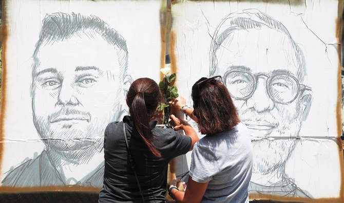 People on Tuesday put white roses on portraits of victims of last year’s Beirut port blast as Lebanon marks the first anniversary of the Aug 4 explosion. (Reuters)