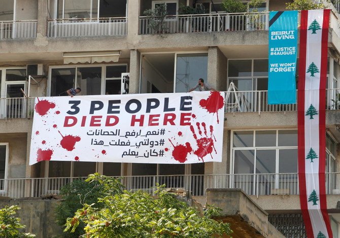 People put a banner on a building as Lebanon marks one-year anniversary of Beirut port explosion, in Beirut, Lebanon August 4, 2021. (Reuters)