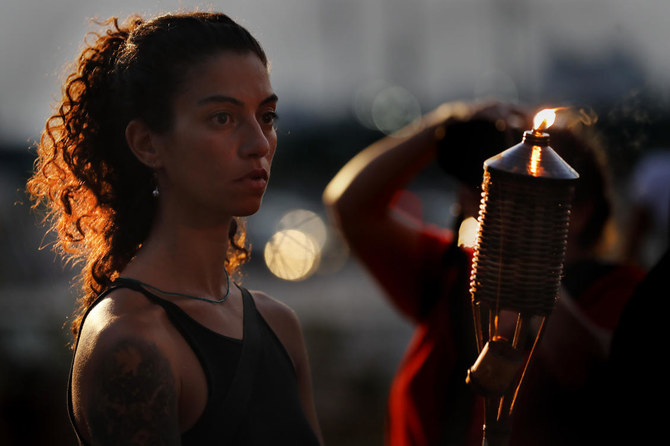 An activist holds a torch during a vigil in honor of those that died in the last August 2020 devastating Beirut Port explosion, in Beirut. (AP)