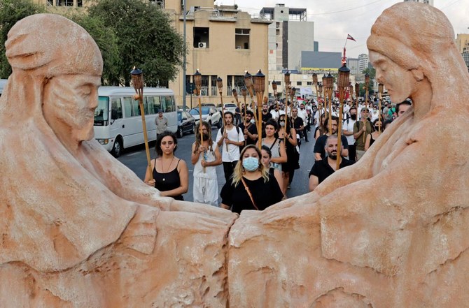 Protesters march with burning torches as they join families of the Beirut blast victims during a symbolic funeral procession from Beirut port. (AFP)