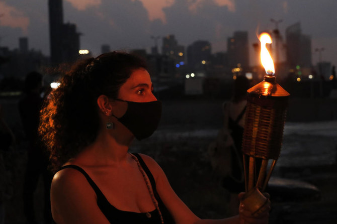 An activist holds a torch during a vigil in honor of those that died in the last August 2020 devastating Beirut Port explosion, in Beirut. (AP)