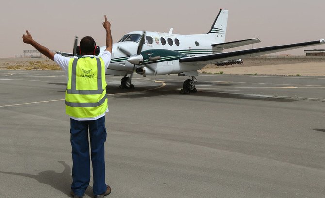 An airport employee signals to a twin-propeller Beechcraft plane as it prepares to take off on a cloud-seeding mission at the UAE's al-Ain airport on April 23, 2015. (AFP)