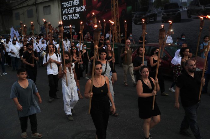Activists hold torches during a vigil in honor August 2020 Beirut Port blast victims. Several Lebanese parties will boycott a parliamentary session called to discuss a proposal to question senior officials. (AP)