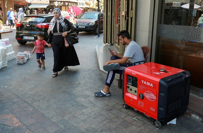 A woman with a child walk past a portable generator, which provides electricity, in Sidon, Lebanon, August 11, 2021. (Reuters)