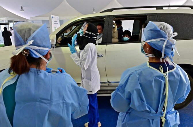 Above, a nurse instructs a driver about the procedure of the coronavirus COVID-19 testing at a drive thru verification center Abu Dhabi on April 2, 2020. (AFP)