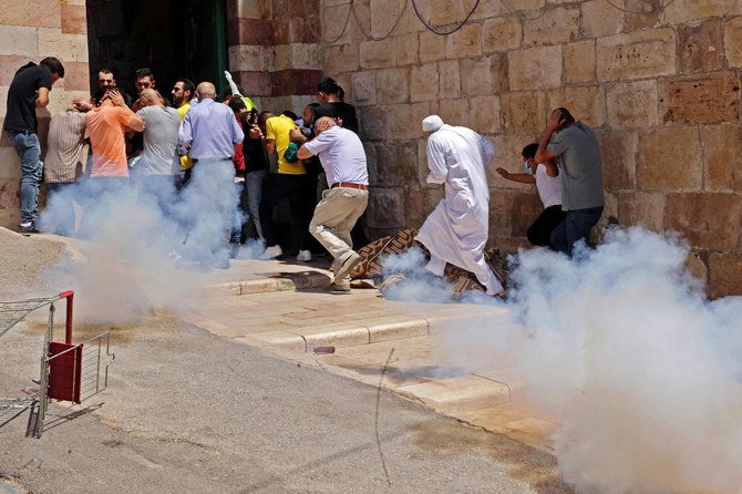 Palestinian worshippers speed away to avoid tear gas amid clashes with Israeli security forces in the divided city of Hebron in the Israeli-occupied West Bank on August 13, 2021. (AFP)