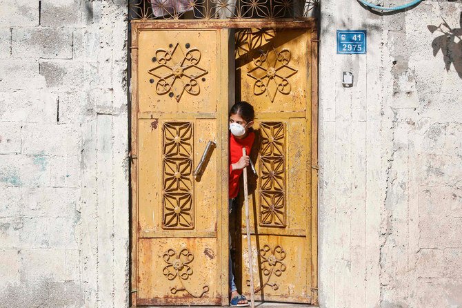 A girl wearing a protective N95 mask sweeps outside her home in Gaza City. (AFP file photo)