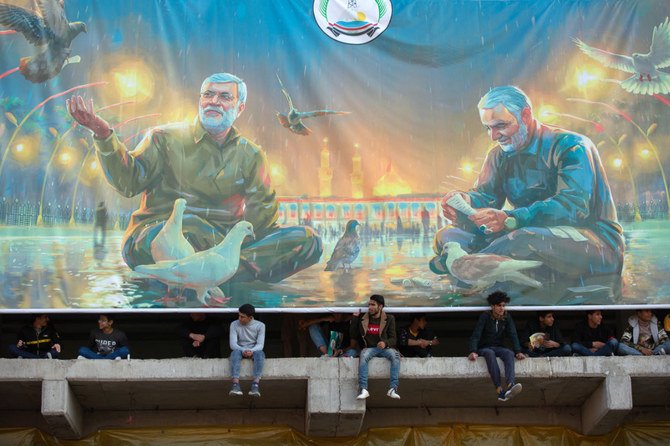 Iraqi youths watch an event celebrating the inauguration of a street named after the late Iraqi commander Abu Mahdi al-Muhandis in Basra on January 8, 2021. (AFP)