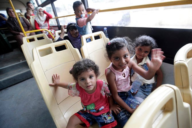 Syrian refugees wave from on board a bus in a Beirut suburb as they prepare to return home to neighboring Syria. (AFP/File)