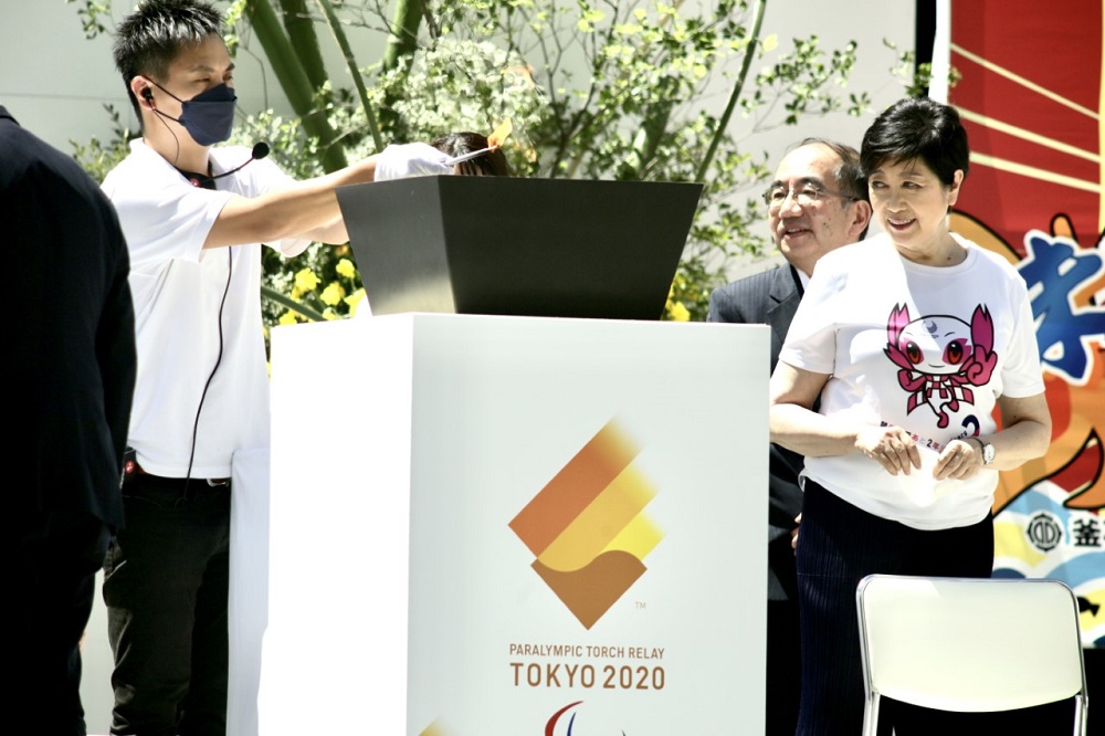 Tokyo governor Yuriko Koike looks on as an official lights up the cauldron during a 