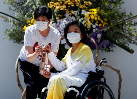 Tokyo 2020 torch relay ambassador Aki Taguchi receives the Paralympic torch lantern from Tokyo Governor Yuriko Koike during the flame gathering event on Friday, August 20, 2021. (Reuters)