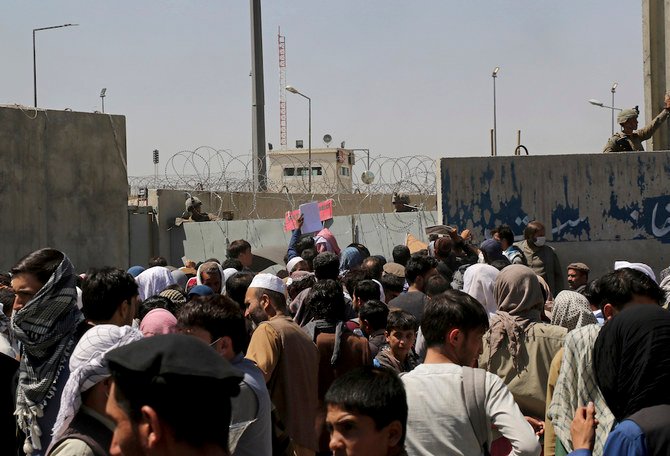 US soldiers stand inside the airport wall as hundreds of people gather near an evacuation control checkpoint on the perimeter of the Hamid Karzai International Airport, in Kabul, Afghanistan. (AP)