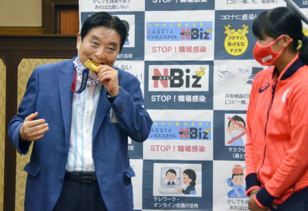 Nagoya city Mayor Takashi Kawamura bites the Tokyo 2020 Olympic Games gold medal of the softball athlete Miu Goto during a ceremony in Nagoya, central Japan, August 4, 2021, in this photo taken by Kyodo. (Reuters)
