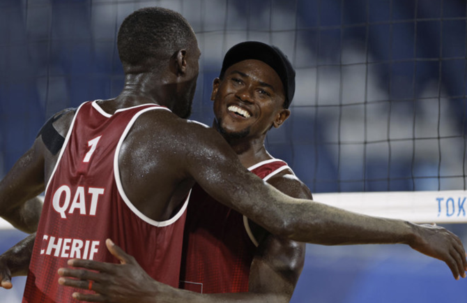 Cherif Younousse (left), of Qatar, and teammate Ahmed Tijan, celebrate winning a men's beach volleyball quarterfinal match against Italy on Aug. 4, 2021. (Reuters)
