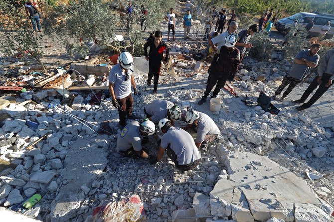 Members of the Syrian Civil Defense search through the rubble of a building that was knocked down by Syrian government forces’ bombardment in the town of Balashun, Idlib province. (File/AFP)