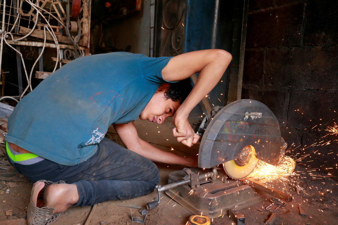 Zakaria Naguib cuts iron bars at a welding workshop in Sanaa, Yemen. (Reuters)