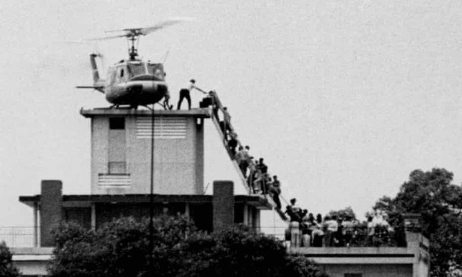 Evacuees are helped aboard an Air America helicopter perched on top of a building in Saigon. (Reuters)
