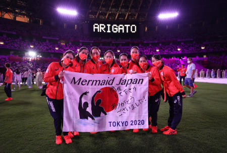 Japanese athletes pose with a flag as a thank you message is displayed inside the stadium during the closing ceremony. (Reuters)