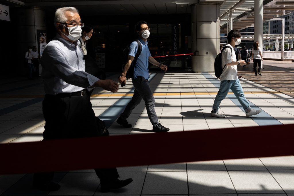 Commuters wear masks at a train station in Tokyo on August 10, 2021, as a coronavirus state of emergency remains in place in the city. (AFP)
