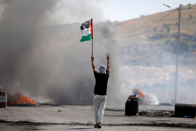 A demonstrator holds a Palestinian flag during a protest at the Hawara checkpoint near Nablus. (Reuters)