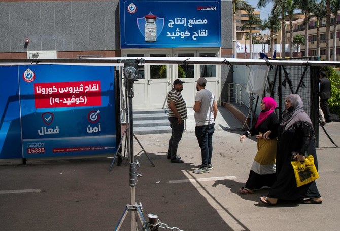 Women walk in front of the Egyptian company VACSERA, wher vials of China's Sinovac vaccine against the coronavirus are produced, in the capital Cairo, on September 1, 2021. (AFP)