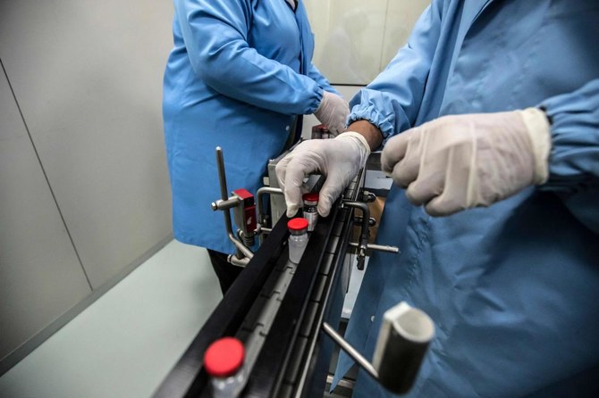 Laboratory workers supervise the production of vials of China's Sinovac vaccine against the coronavirus, produced by the Egyptian company VACSERA, in the capital Cairo, on September 1, 2021. (AFP)
