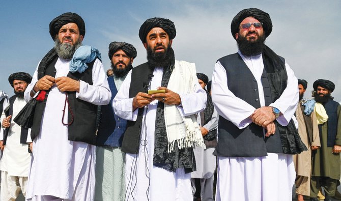 Taliban spokesman Zabihullah Mujahid, center, speaks to the media at the airport in Kabul on Wednesday, after the US pulled all its troops out of the country. (AFP)
