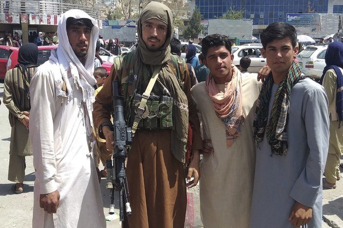 A Taliban fighter (2L) is seen with locals at Pul-e-Khumri on August 11, 2021 after Taliban captured Pul-e-Khumri, the capital of Baghlan province about 200 kms north of Kabul. (File/AFP)