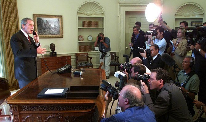 US President George W. Bush stands behind his desk inside the Oval Office of the White House surrounded by the media. (File/AFP)