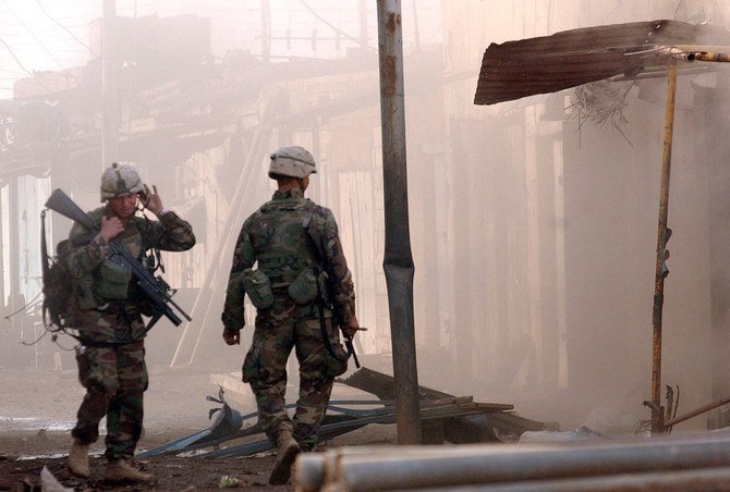 Two US soldiers inspect the damage after a small explosive charge was used to blow the door off a store in the industrial section of Samarra, 17 December, 2003. (File/AFP)