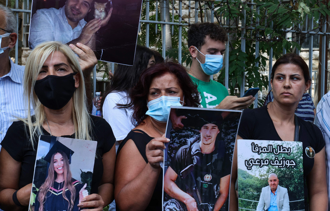 Activists and relatives of victims of the Beirut port blast lift placards as they demonstrate on Sep. 29, 2021 outside the Beirut's Justice Palace, to protest the suspension of the probe into the Aug. 4, 2020 port explosion. (AFP)