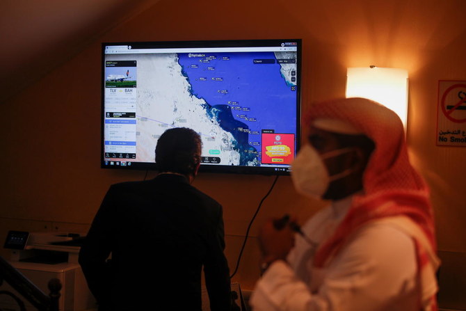 Bahraini officials stand near the screen showing the live flight of Israeli Foreign Minister Yair Lapid on-screen at Bahrain International Airport in Muharraq on Sept. 30, 2021. (Reuters)