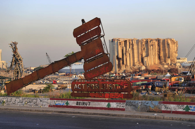 A monument demanding justice stands before grain silos that were gutted in the August 2020, Beirut port explosion. (AP Photo)