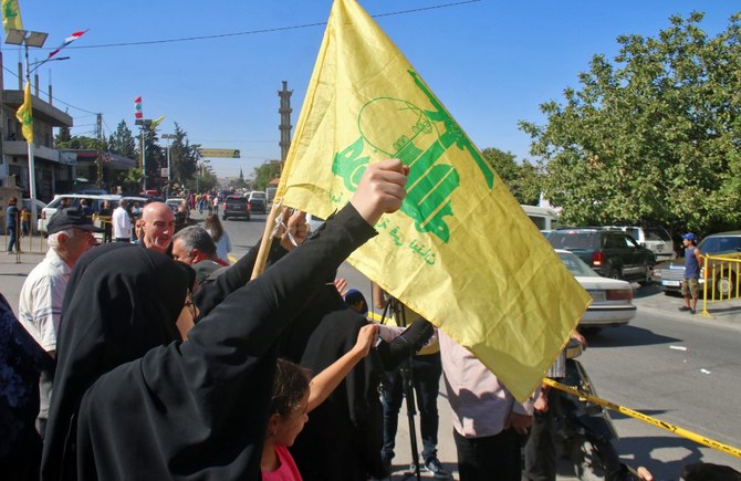 Lebanese people wave a Hezbollah flag as tankers carrying Iranian fuel arrive from Syria. (File/AFP)