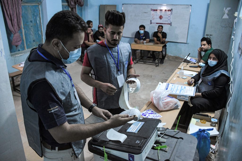 Iraqi election officials print out the electronic count of votes at a polling station in the southern city of Nasiriyah in Dhi Qar province, during the early parliamentary elections on October 10, 2021. (AFP)