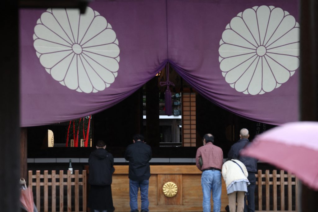 People pray in front of a wooden plaque showing the name of Japan's Prime Minister Fumio Kishida seen with a 