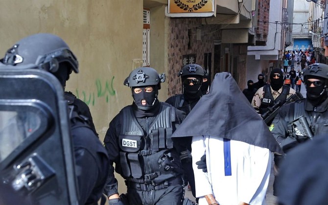 Members of Morocco’s Central Bureau of Judicial Investigation, which oversees counter-terrorism operations, escort a suspect outside a house in the city of Tangier on Wednesday. (AFP)