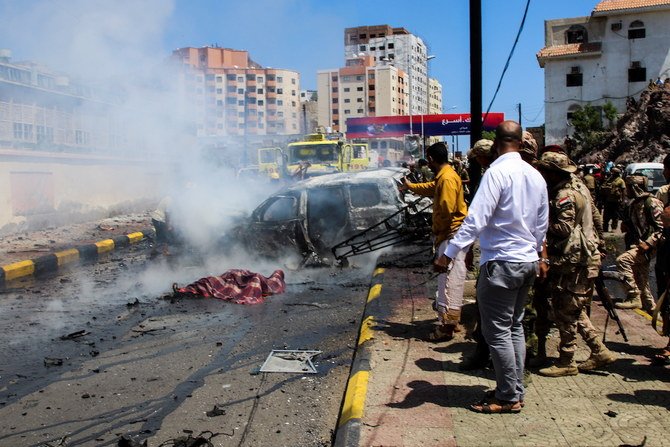 People look at bodies of dead people covered with a blanket at the scene of a blast in Aden. (Reuters)