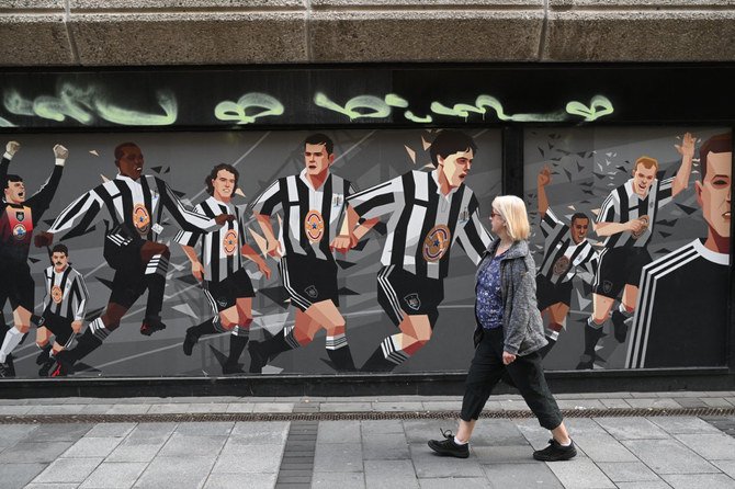 A pedestrian passes a Newcastle United football club-themed mural in Newcastle upon Tyne in northeast England on October 8, 2021. (Photo by Oli Scarff / AFP)