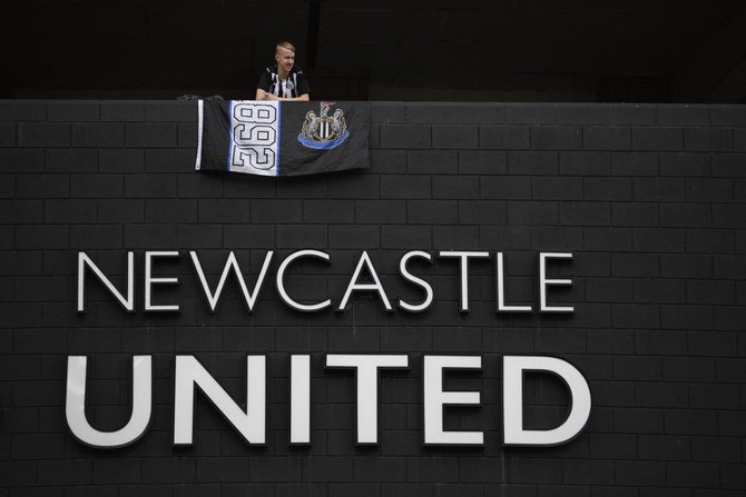 A Newcastle United football club supporter stands with a flag above the club logo at their stadium St James' Park in Newcastle upon Tyne in northeast England on Oct. 8, 2021. (Photo by Oli Scarff / AFP)