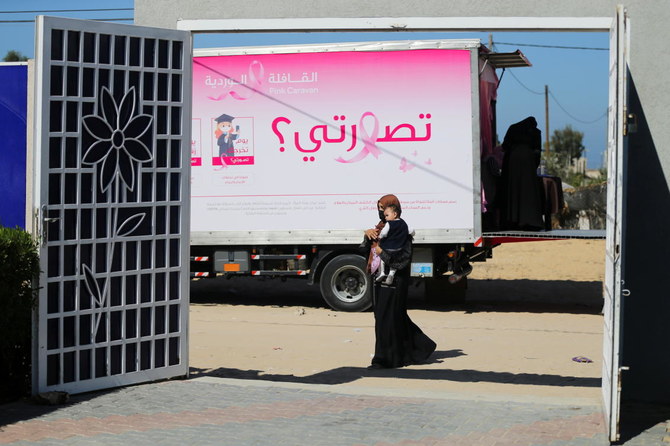A Palestinian woman with a child walks past a mobile breast cancer check up clinic set up in a truck. Picture taken October 7, 2021. (Reuters)