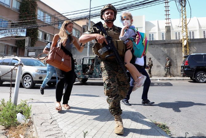 An army soldier carries a schoolchild as civilians flee after gunfire erupted erupted in Beirut. (Reuters)