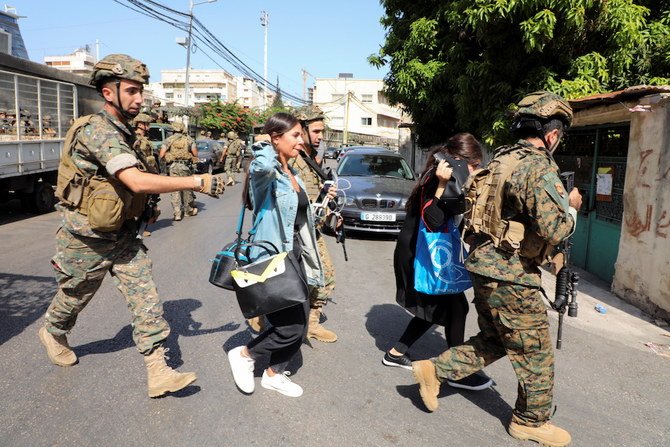 An army soldier carries a schoolchild as civilians flee after gunfire erupted erupted in Beirut. (Reuters)