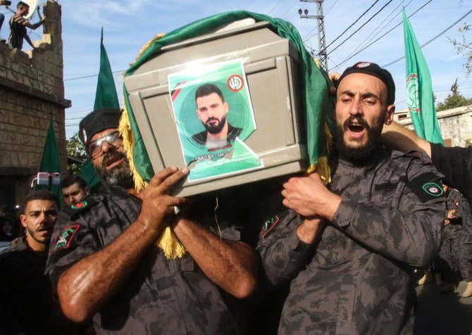 Shiite Amal movement’s members carry the flag-draped casket of a fellow fighter, who was killed in the Tayouneh clashes on Thursday, during his funeral in Al-Numairiyah village on Friday. Lebanon today buried victims of its deadliest sectarian unrest in years. (AFP)